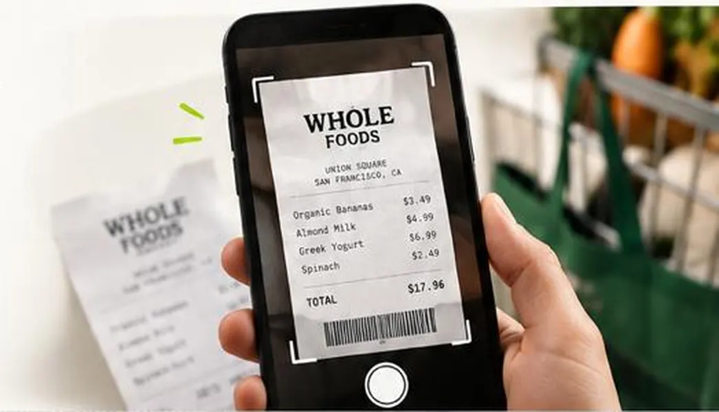A phone camera framing a Whole Foods invoice, with the grocery bag behind